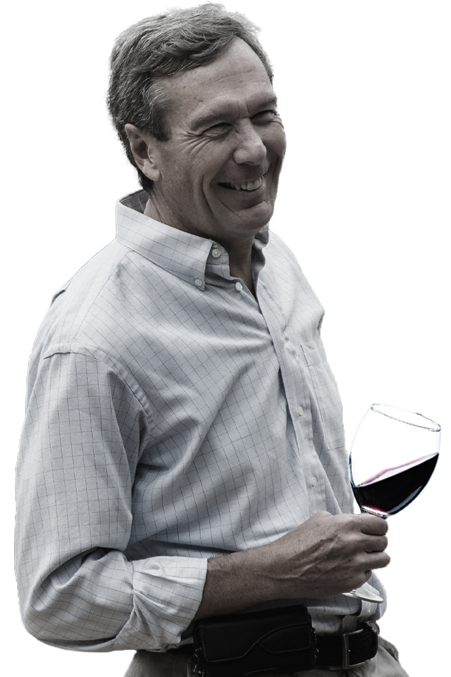 Bill Stoller, founder of Stoller Family Estate, laughing and holding a glass of estate Pinot Noir